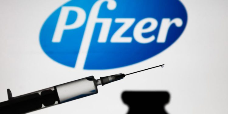 Medical syringe is seen with Pfizer company logo displayed on a screen in the background in this illustration photo taken in Poland on November 16, 2020. (Photo by Jakub Porzycki/NurPhoto via Getty Images)