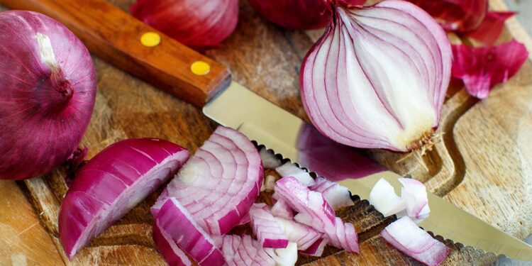 Red onions on a wooden board close up